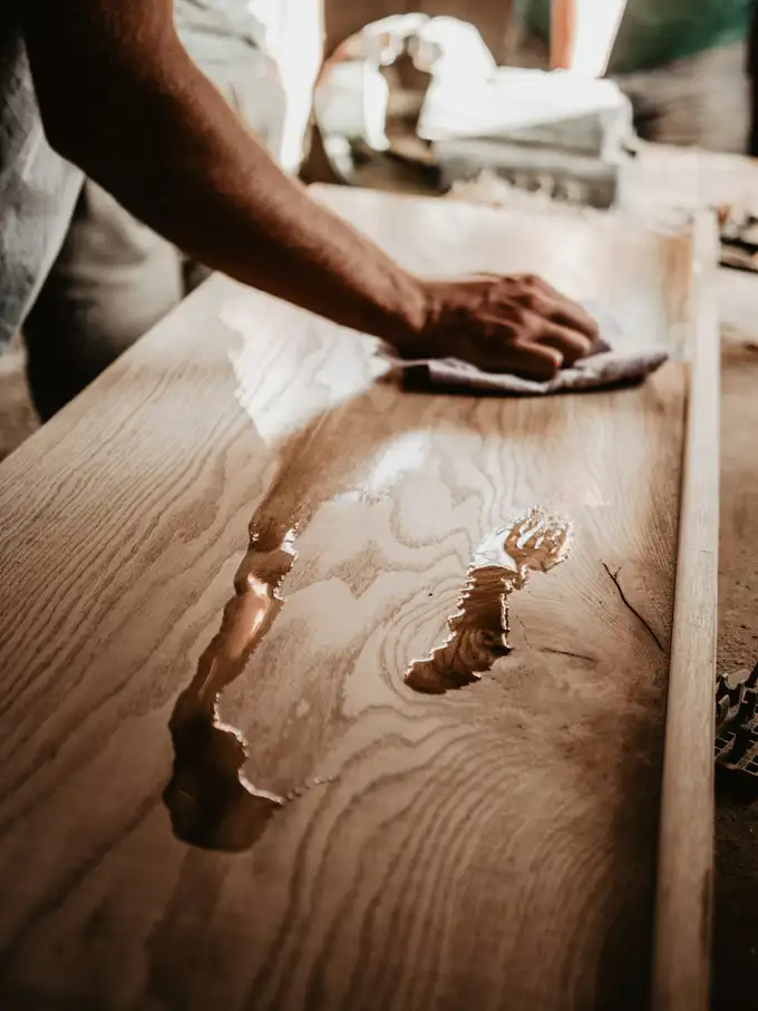 Application d’huile au chiffon sur un plateau en bois massif dont le fil ressort