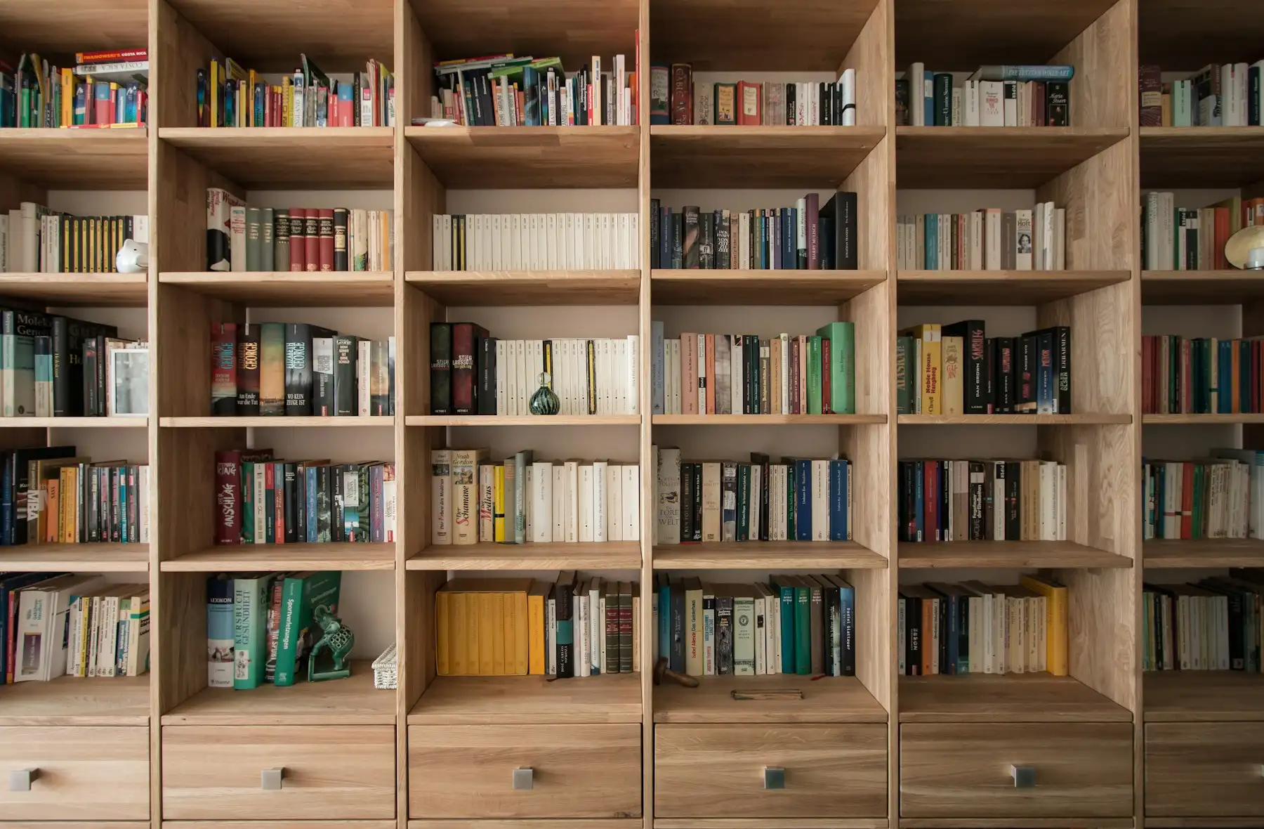 Bibliothèque murale en chêne massif sur mesure, casiers garnis de livres et tiroirs en partie basse