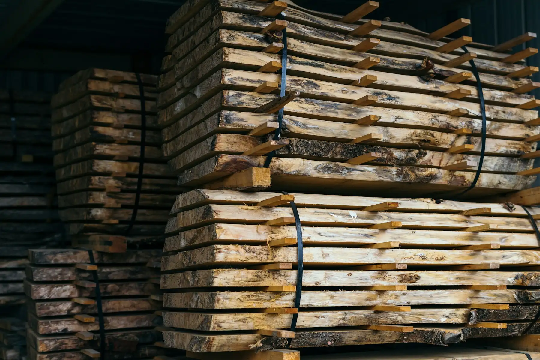 Plateaux de bois avivés empilés sur lattes et cerclés, au séchage sous abri