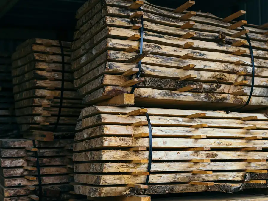 Plateaux de bois avivés empilés sur lattes et cerclés, au séchage sous abri