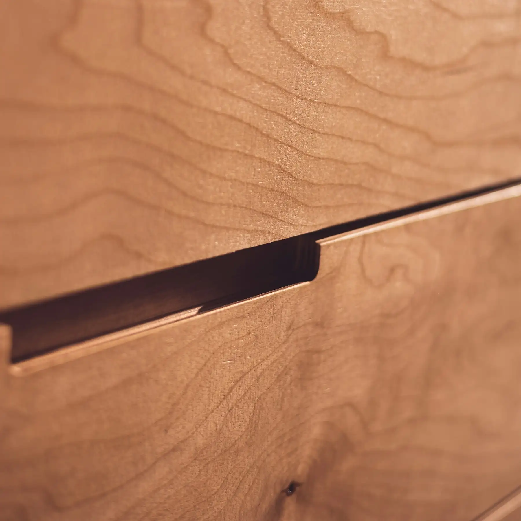 Détail d’un tiroir en bois avec prise de main usinée dans le chant