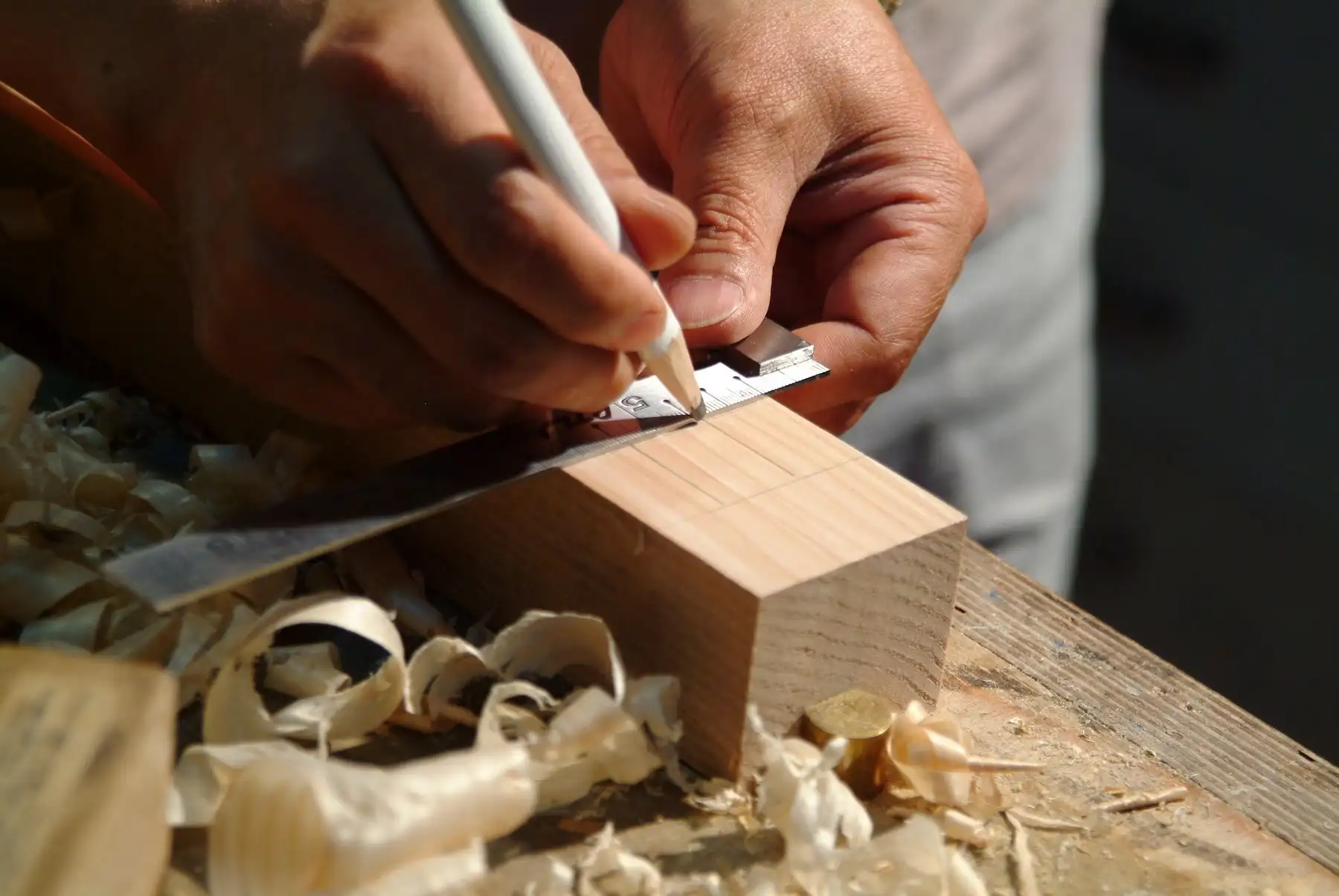 Traçage à l’équerre sur le chant d’une pièce de bois, copeaux sur l’établi